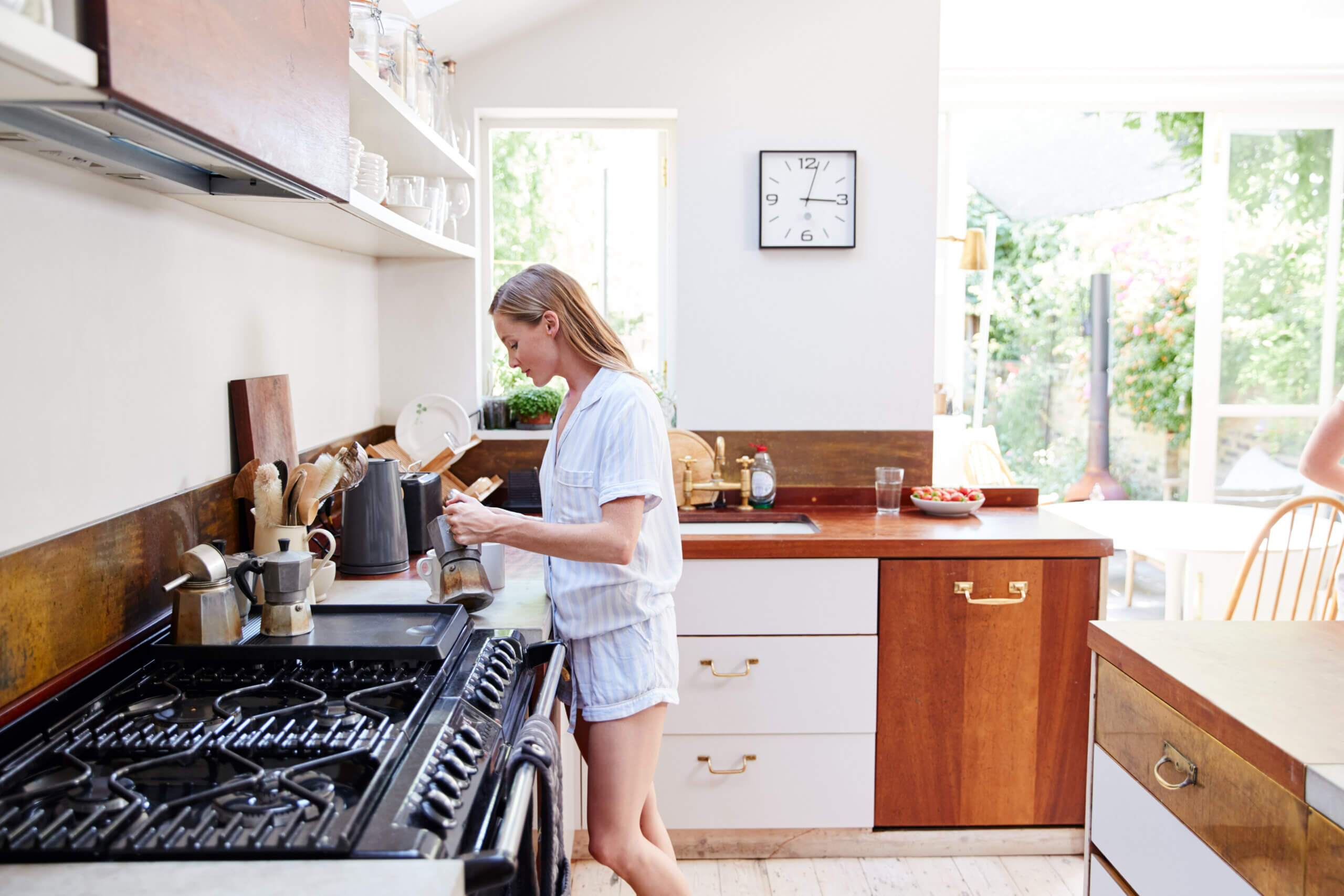 woman at home in pajamas in kitchen making coffee